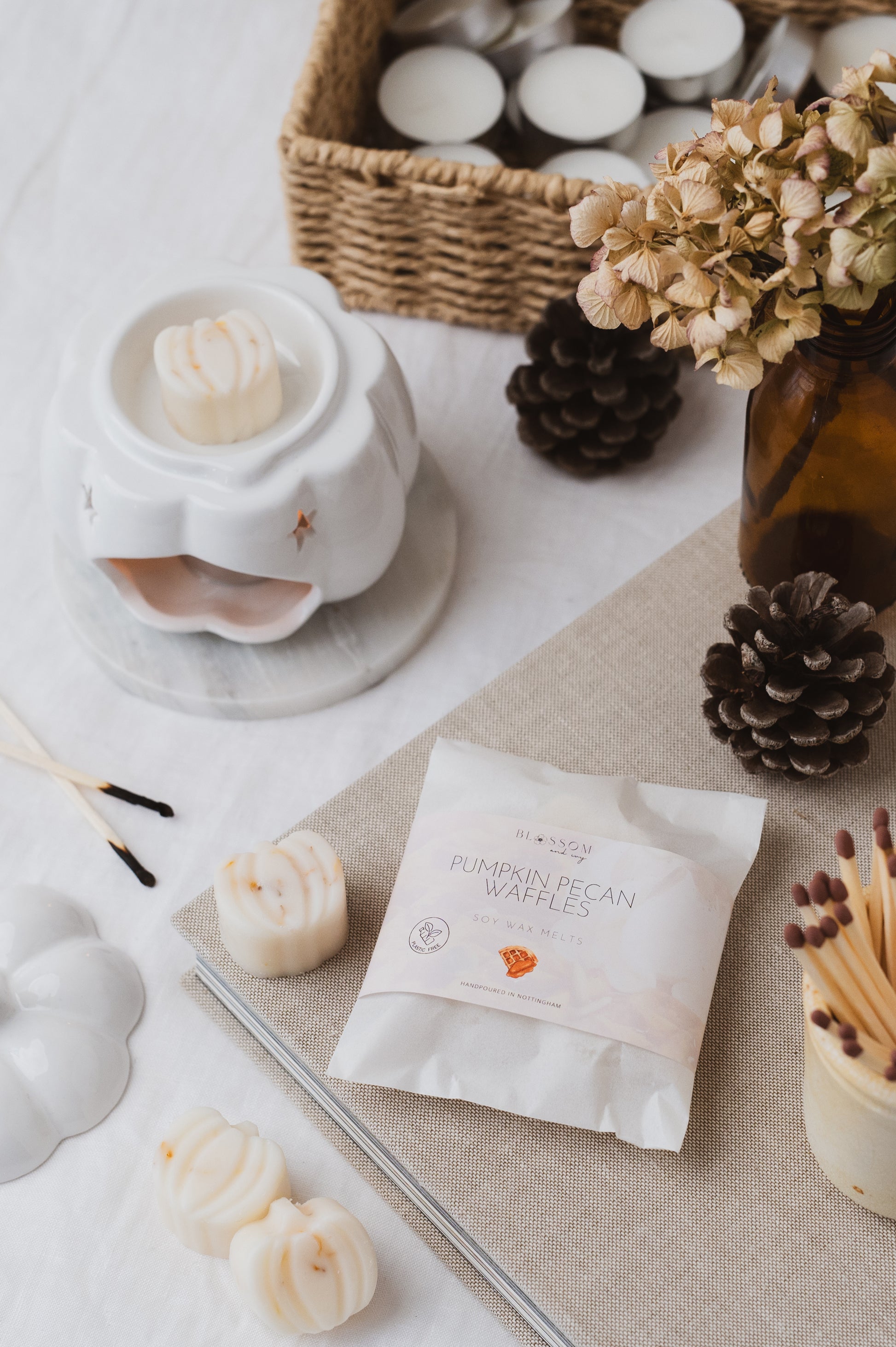 Pumpkin Pecan Waffles botanical soy wax melts displayed on a book, with a pumpkin-shaped wax melt burning in a wax burner.