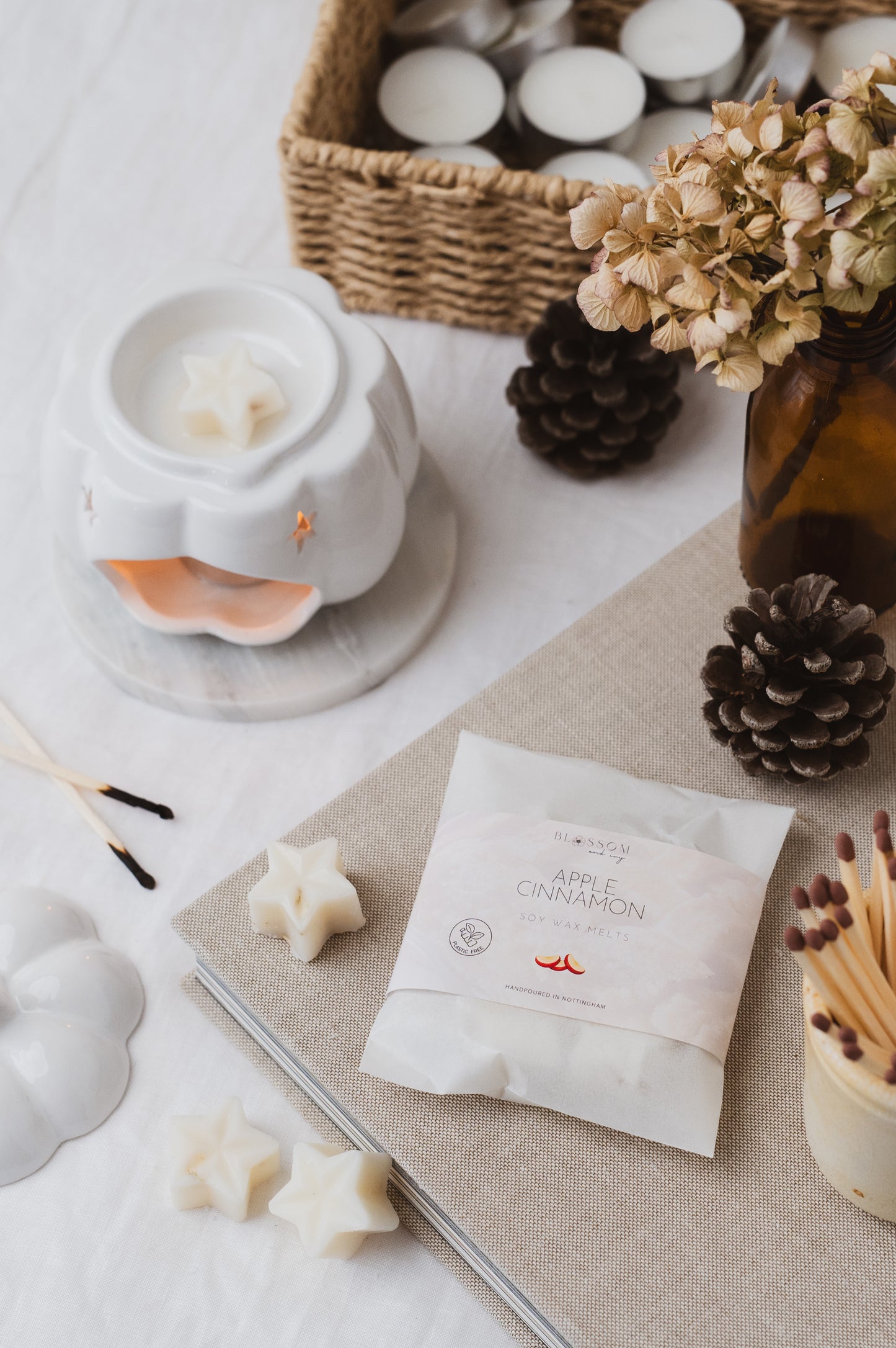 Apple and Cinnamon botanical wax melts resting on a book. Star-shaped wax melt has been added into the wax burner and is melting.