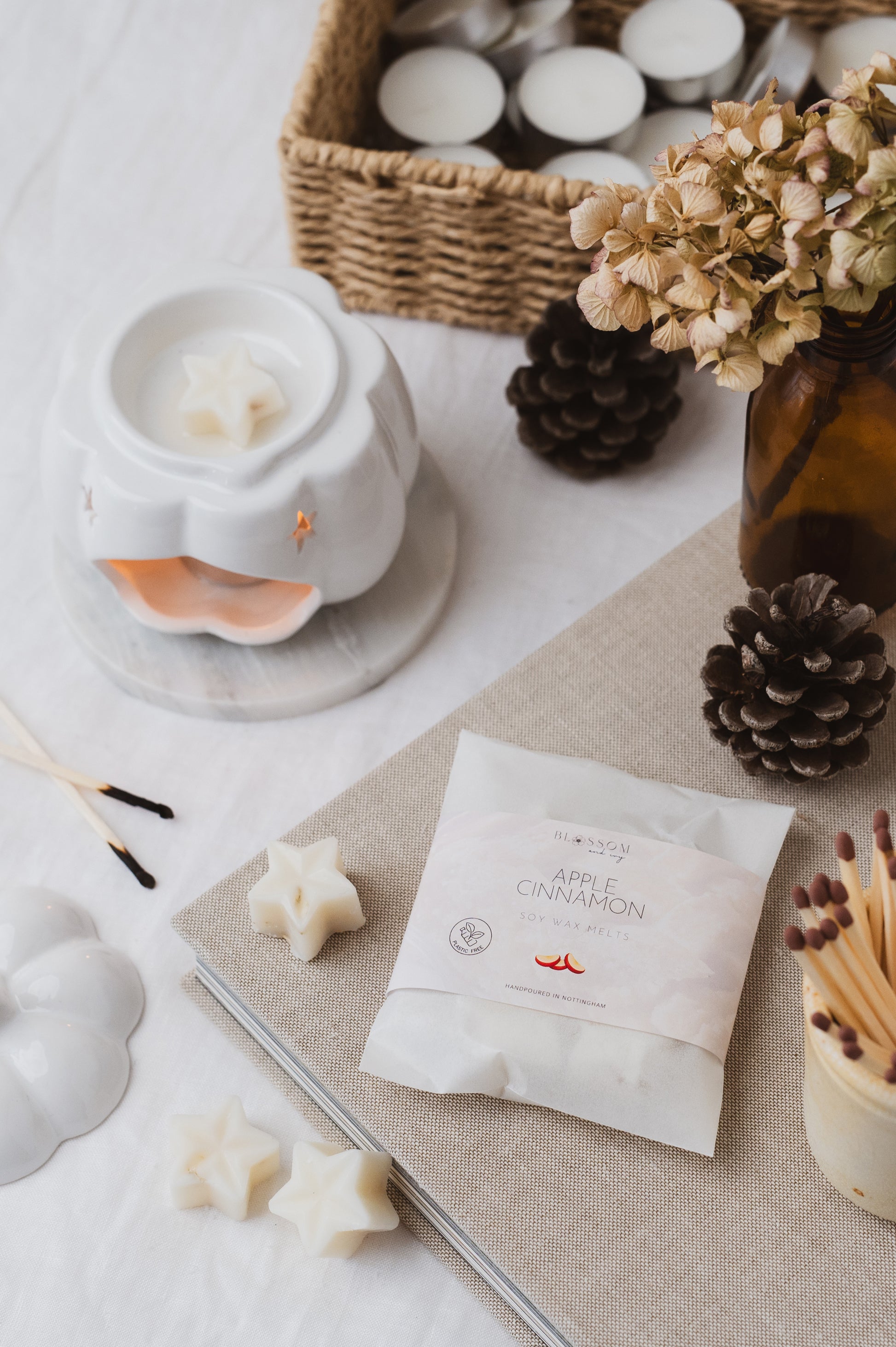 Apple and Cinnamon botanical wax melts resting on a book. Star-shaped wax melt has been added into the wax burner and is melting.